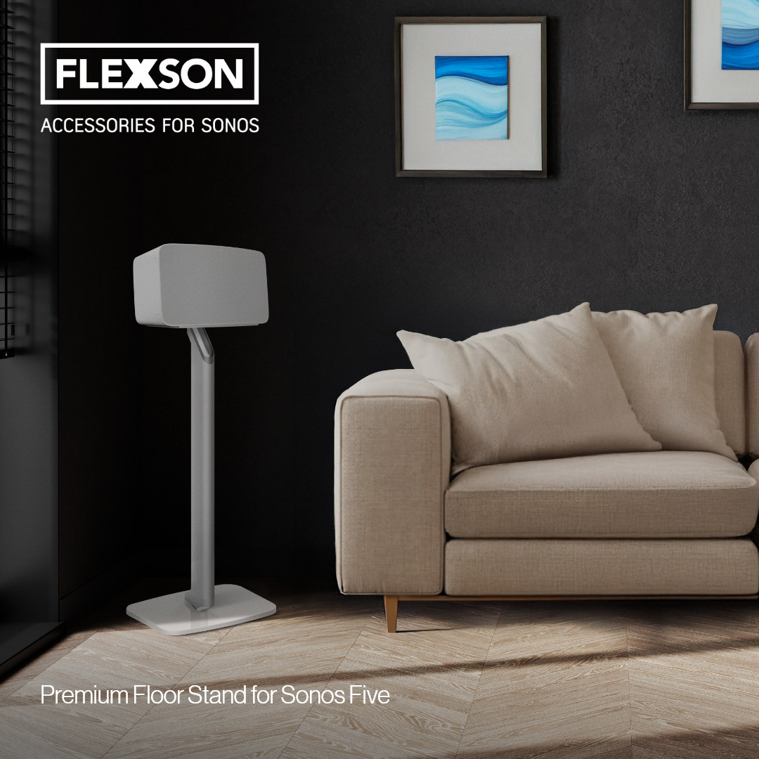 Ein weißer Sonos Play:5 steht neben einer Couch auf einem Standfuß.